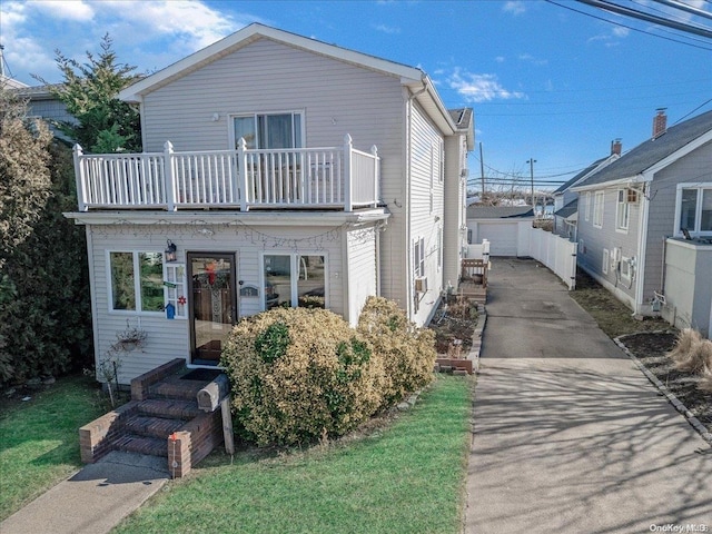 view of front facade with a balcony, an outbuilding, and a garage