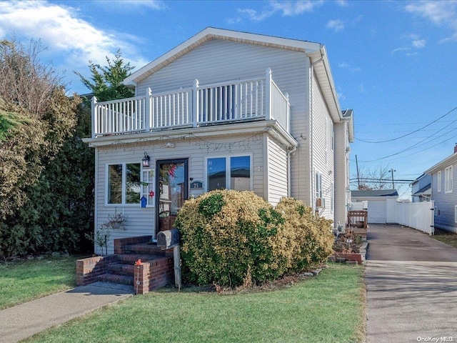 view of front of house featuring a balcony, a front yard, an outdoor structure, and a garage