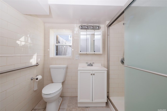 bathroom featuring tile patterned floors, vanity, a shower with door, tile walls, and toilet