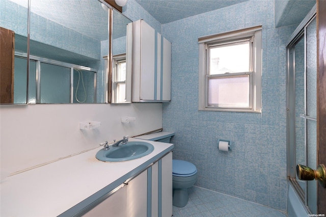 full bathroom featuring combined bath / shower with glass door, vanity, tile walls, tile patterned flooring, and toilet