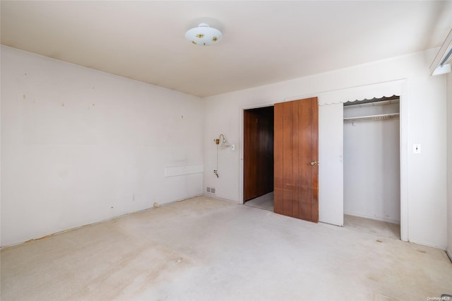 unfurnished bedroom with light colored carpet and a closet