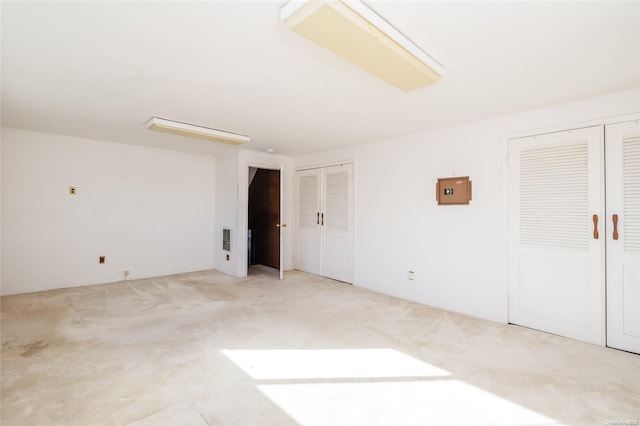 unfurnished bedroom featuring multiple closets and light colored carpet