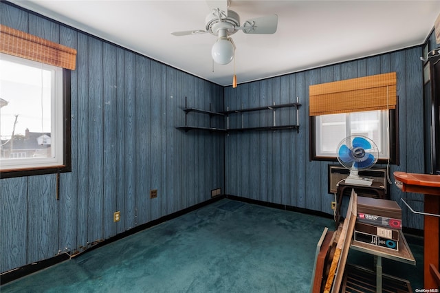 empty room with ceiling fan and dark colored carpet