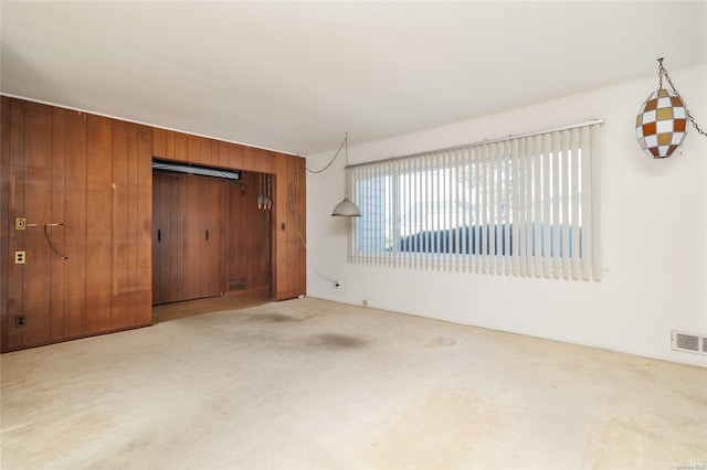 interior space featuring light colored carpet and wooden walls