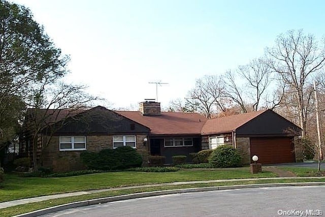 single story home featuring a chimney, a front yard, a garage, stone siding, and driveway