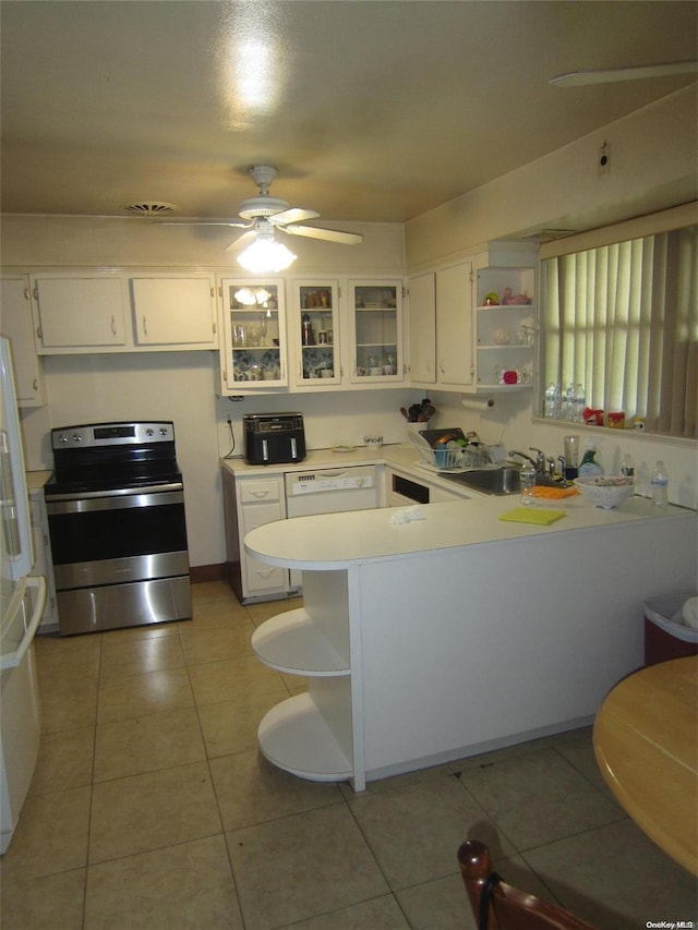 kitchen featuring a peninsula, a sink, light countertops, stainless steel electric range oven, and glass insert cabinets