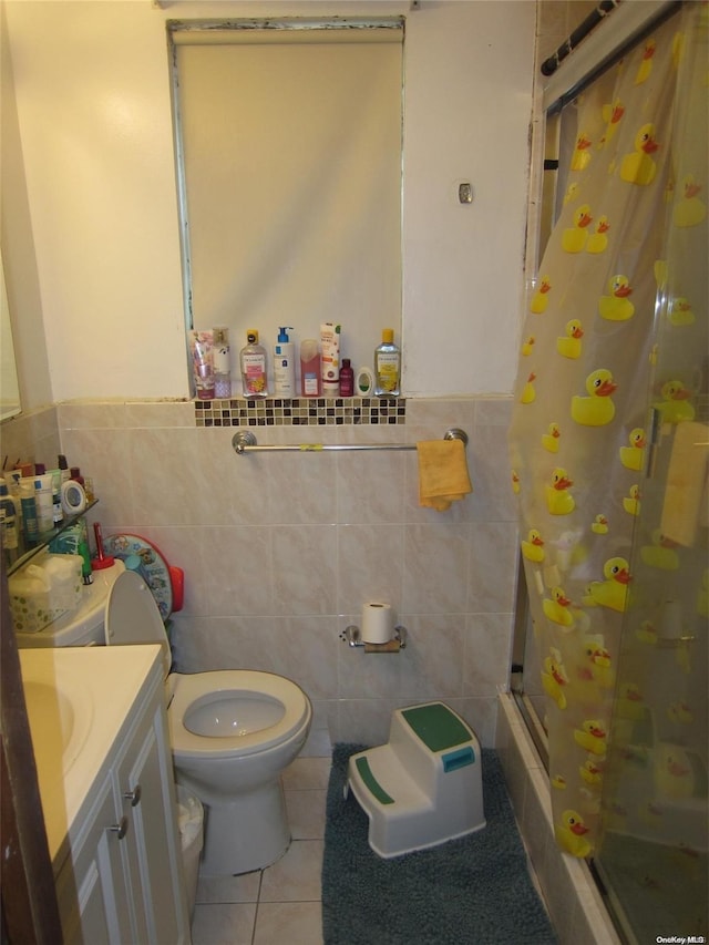 bathroom featuring toilet, tile walls, vanity, tile patterned floors, and a stall shower