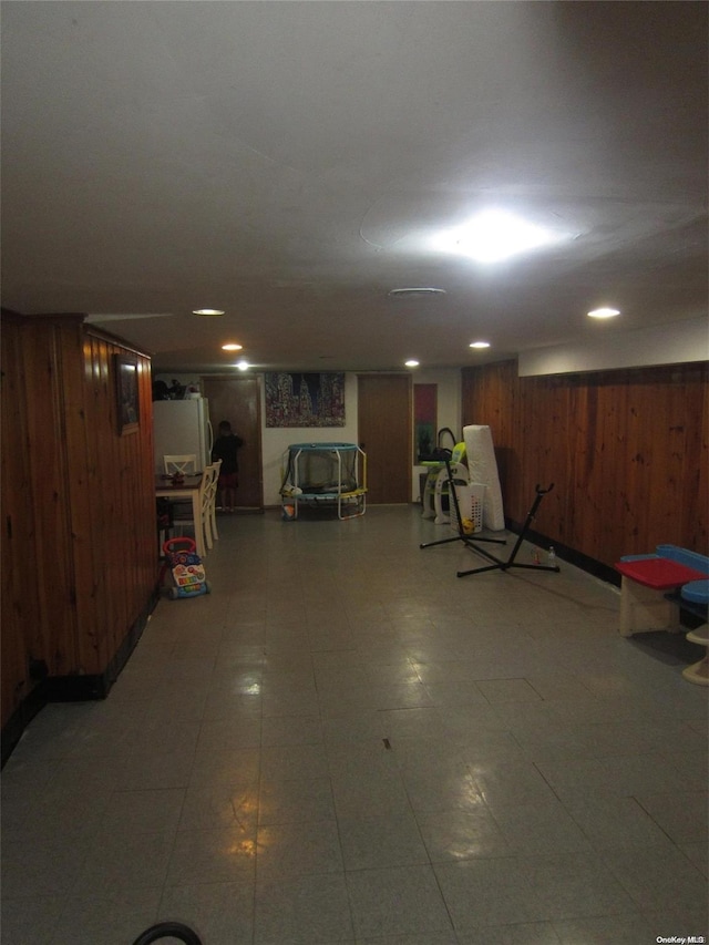 finished basement featuring wood walls and freestanding refrigerator