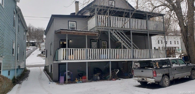 snow covered rear of property featuring a balcony