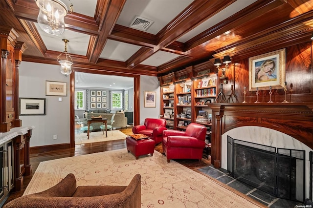 sitting room with dark wood-type flooring, coffered ceiling, ornamental molding, a fireplace, and beamed ceiling