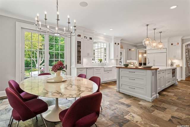 dining space with crown molding, sink, and an inviting chandelier