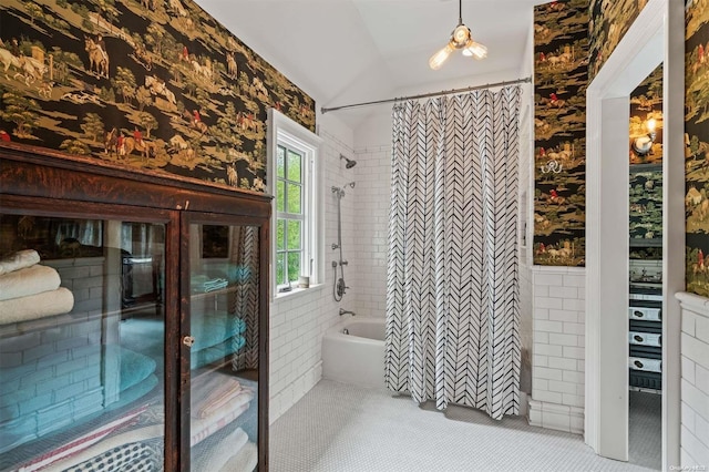 bathroom featuring tile patterned floors, tile walls, and vaulted ceiling