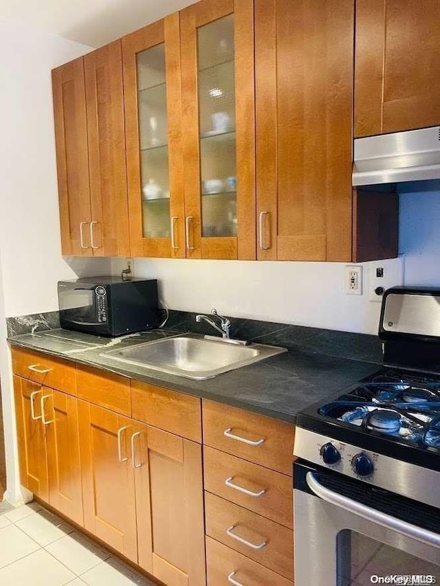 kitchen with exhaust hood, light tile patterned floors, stainless steel gas range oven, and sink