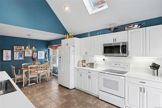 kitchen with a skylight, white cabinetry, a notable chandelier, pendant lighting, and white appliances