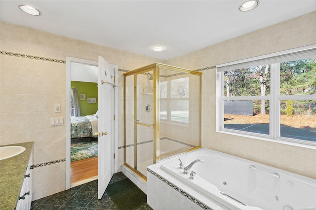 bathroom with tile patterned floors, vanity, plus walk in shower, and tile walls