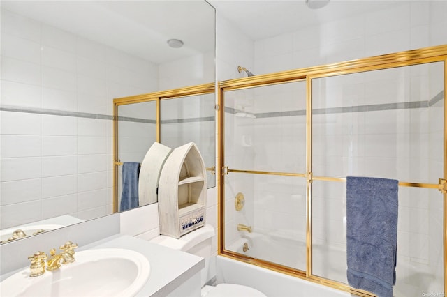 full bathroom featuring vanity, bath / shower combo with glass door, and toilet