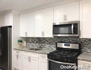 kitchen with white cabinetry, sink, light stone countertops, and appliances with stainless steel finishes