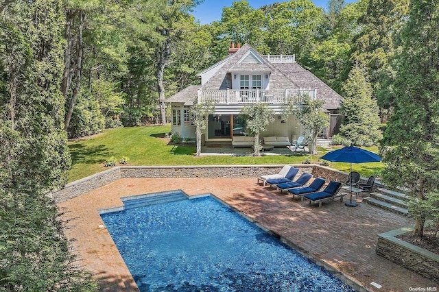 back of house with an outdoor living space, a balcony, a yard, and a patio