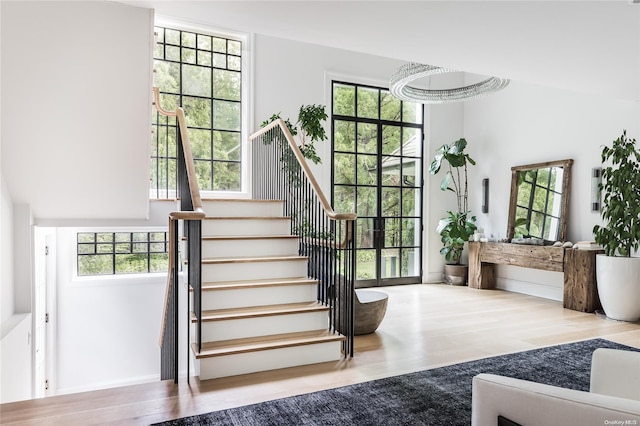 stairs featuring hardwood / wood-style floors, a wealth of natural light, and a chandelier