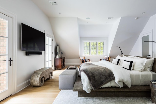 bedroom with multiple windows, light hardwood / wood-style flooring, lofted ceiling, and access to exterior