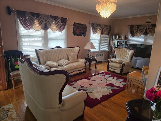 living room with hardwood / wood-style flooring, an inviting chandelier, plenty of natural light, and crown molding