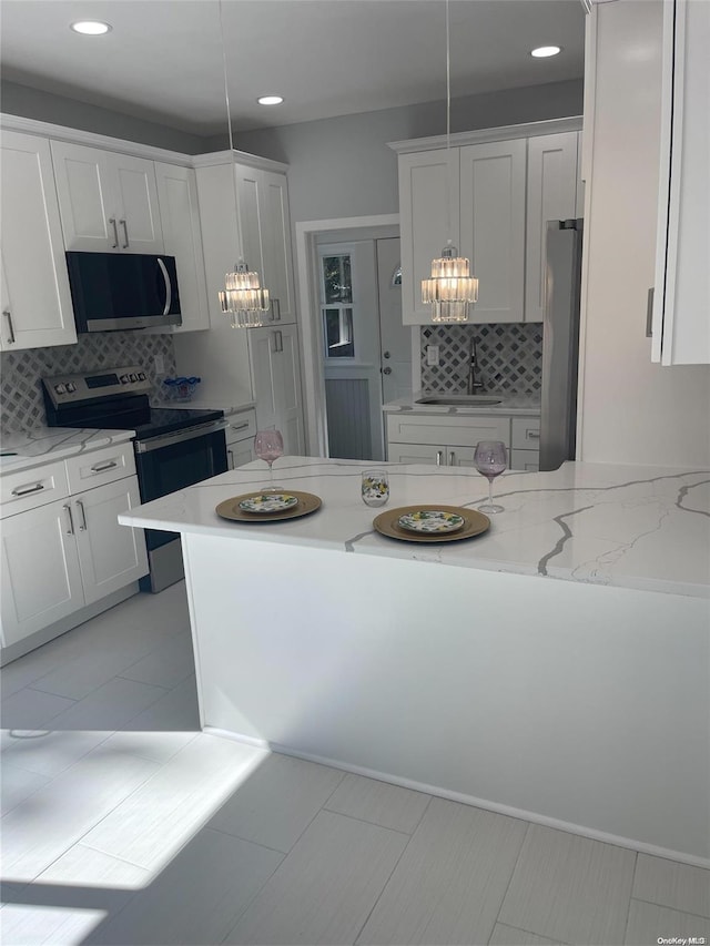 kitchen with backsplash, stainless steel appliances, sink, pendant lighting, and white cabinets