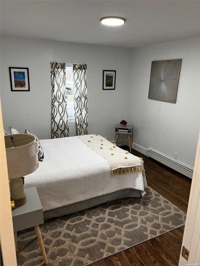 bedroom with dark wood-type flooring and a baseboard heating unit