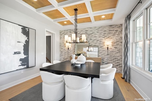 dining area featuring beam ceiling, light hardwood / wood-style flooring, coffered ceiling, and a notable chandelier