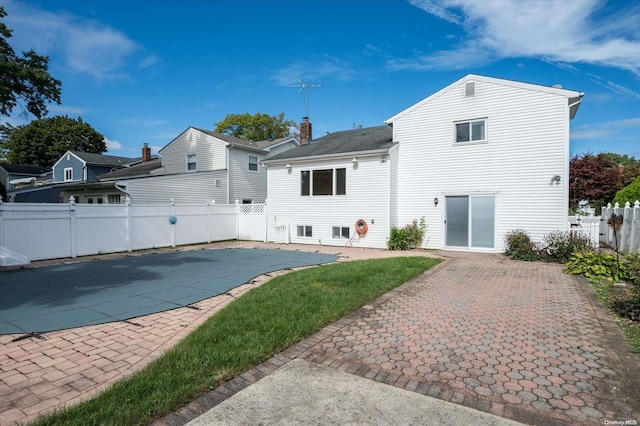 back of property with a patio area and a covered pool