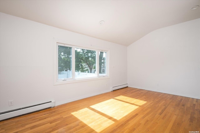 empty room featuring baseboard heating, light hardwood / wood-style floors, and lofted ceiling