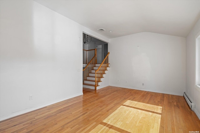 empty room with lofted ceiling, hardwood / wood-style flooring, and a baseboard heating unit