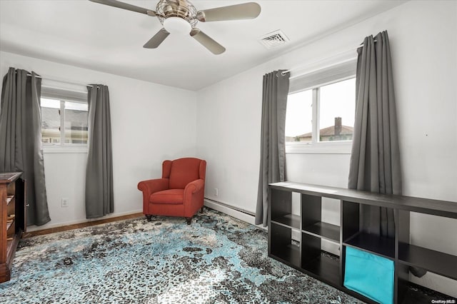 sitting room featuring a wealth of natural light, ceiling fan, a baseboard radiator, and hardwood / wood-style flooring