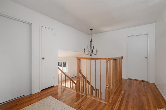 hall with wood-type flooring and an inviting chandelier