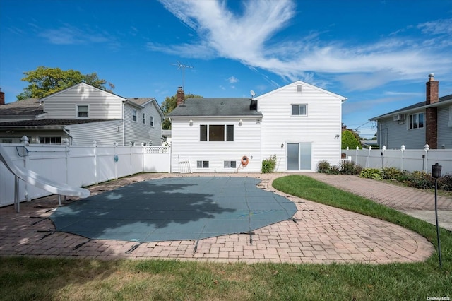 rear view of property with a patio and a covered pool