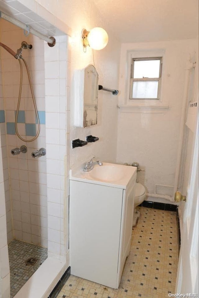 bathroom featuring vanity, toilet, and tiled shower