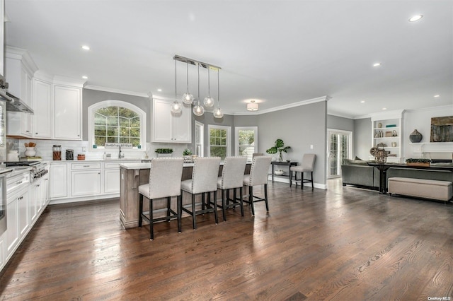 kitchen with a kitchen breakfast bar, dark wood-type flooring, decorative light fixtures, white cabinets, and a kitchen island