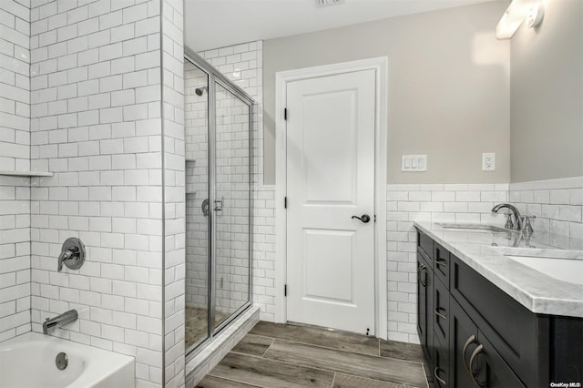 bathroom with vanity, tiled shower / bath combo, tile walls, and hardwood / wood-style flooring