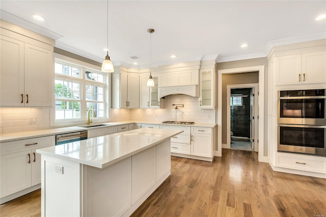 kitchen with stainless steel appliances, tasteful backsplash, hanging light fixtures, a kitchen island, and sink