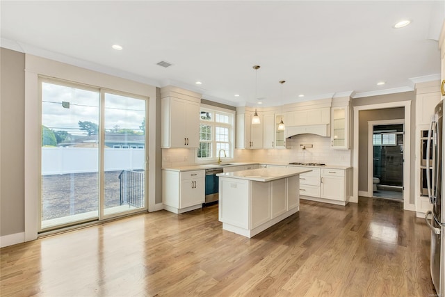 kitchen with dishwasher, a center island, decorative light fixtures, light hardwood / wood-style flooring, and crown molding