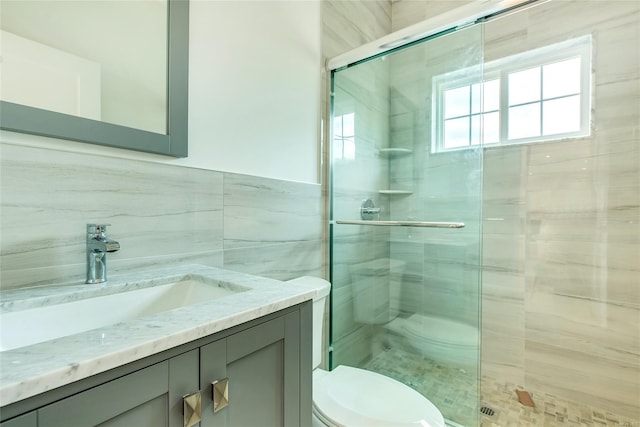 bathroom featuring toilet, vanity, tile walls, and walk in shower