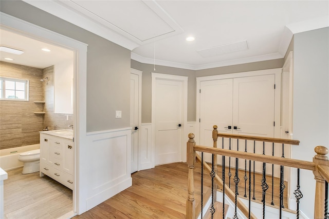 hallway with light hardwood / wood-style floors and crown molding