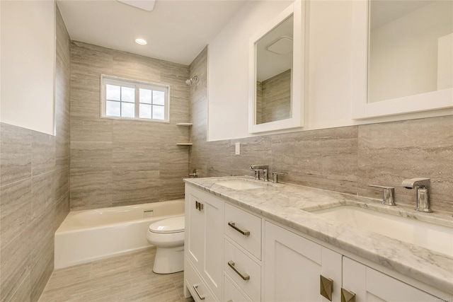 full bathroom featuring toilet, tiled shower / bath combo, tile walls, and vanity