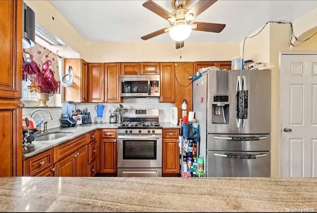 kitchen with decorative backsplash, sink, stainless steel appliances, and light stone counters