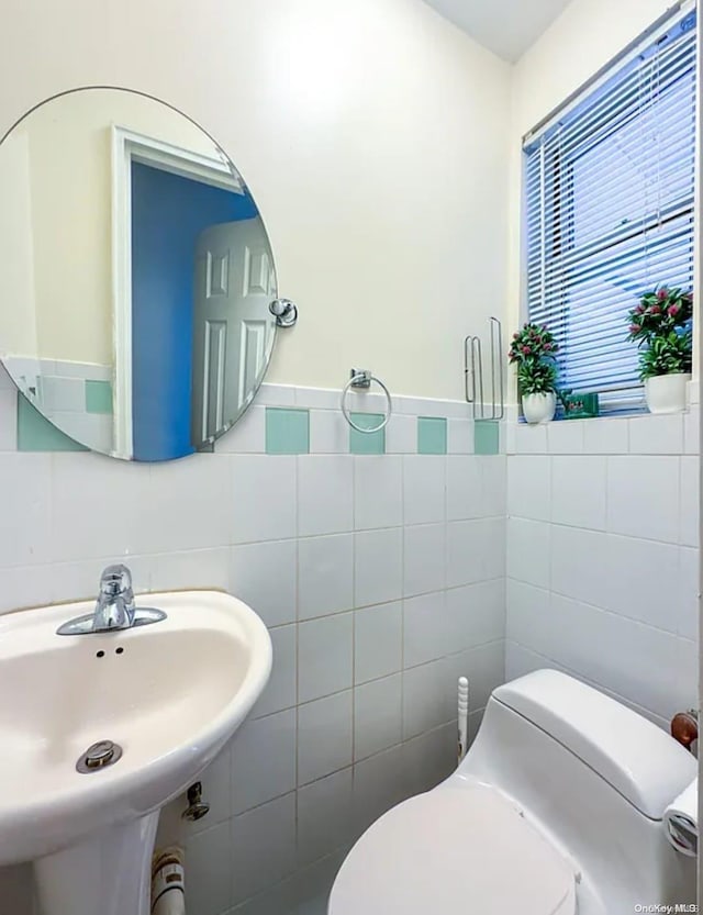 bathroom featuring toilet, sink, and tile walls