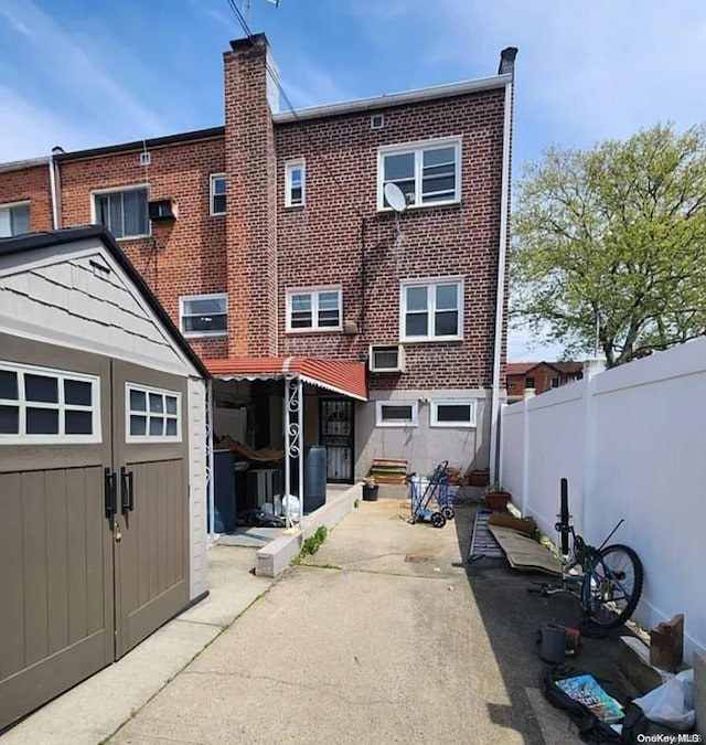 back of property with a shed and a patio area