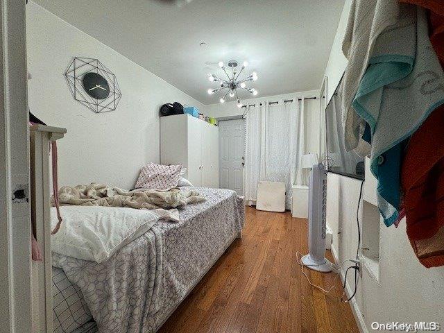 bedroom with hardwood / wood-style flooring and a notable chandelier