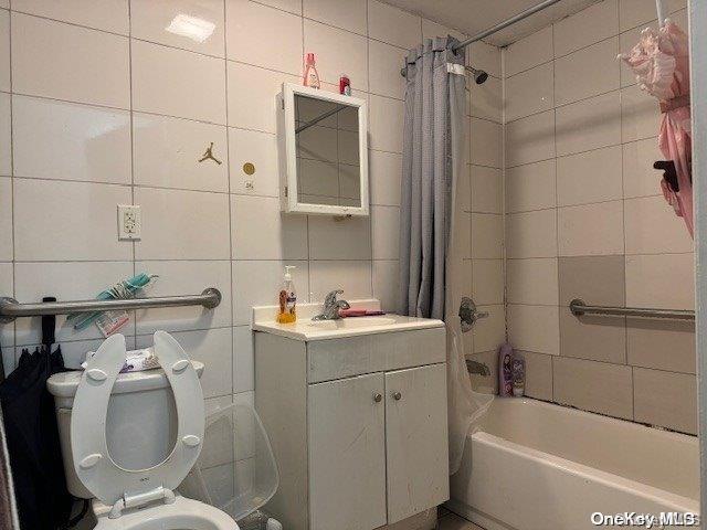 full bathroom featuring shower / bath combination with curtain, toilet, decorative backsplash, vanity, and tile walls