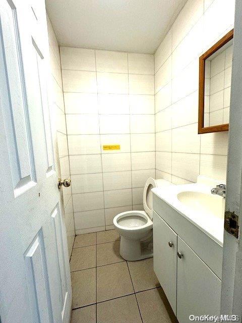 bathroom with tile patterned floors, vanity, tile walls, and toilet