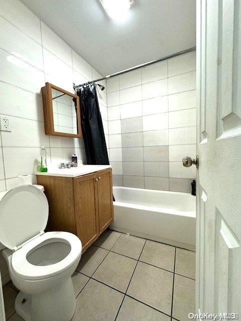 full bathroom with vanity, tile patterned flooring, toilet, tile walls, and shower / tub combo with curtain