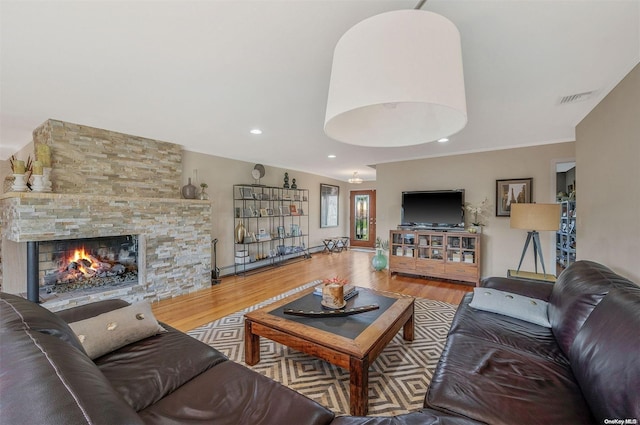 living room featuring hardwood / wood-style floors, crown molding, and a fireplace